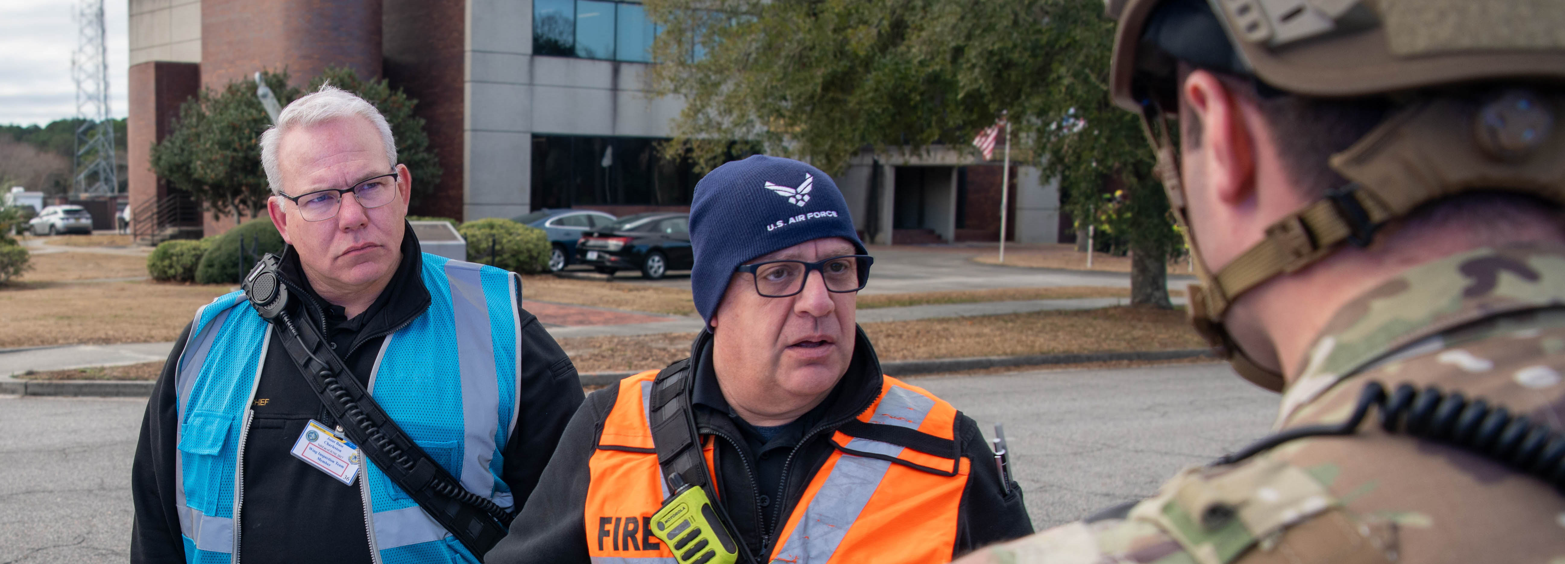 A photo of three men standing outside conversing.